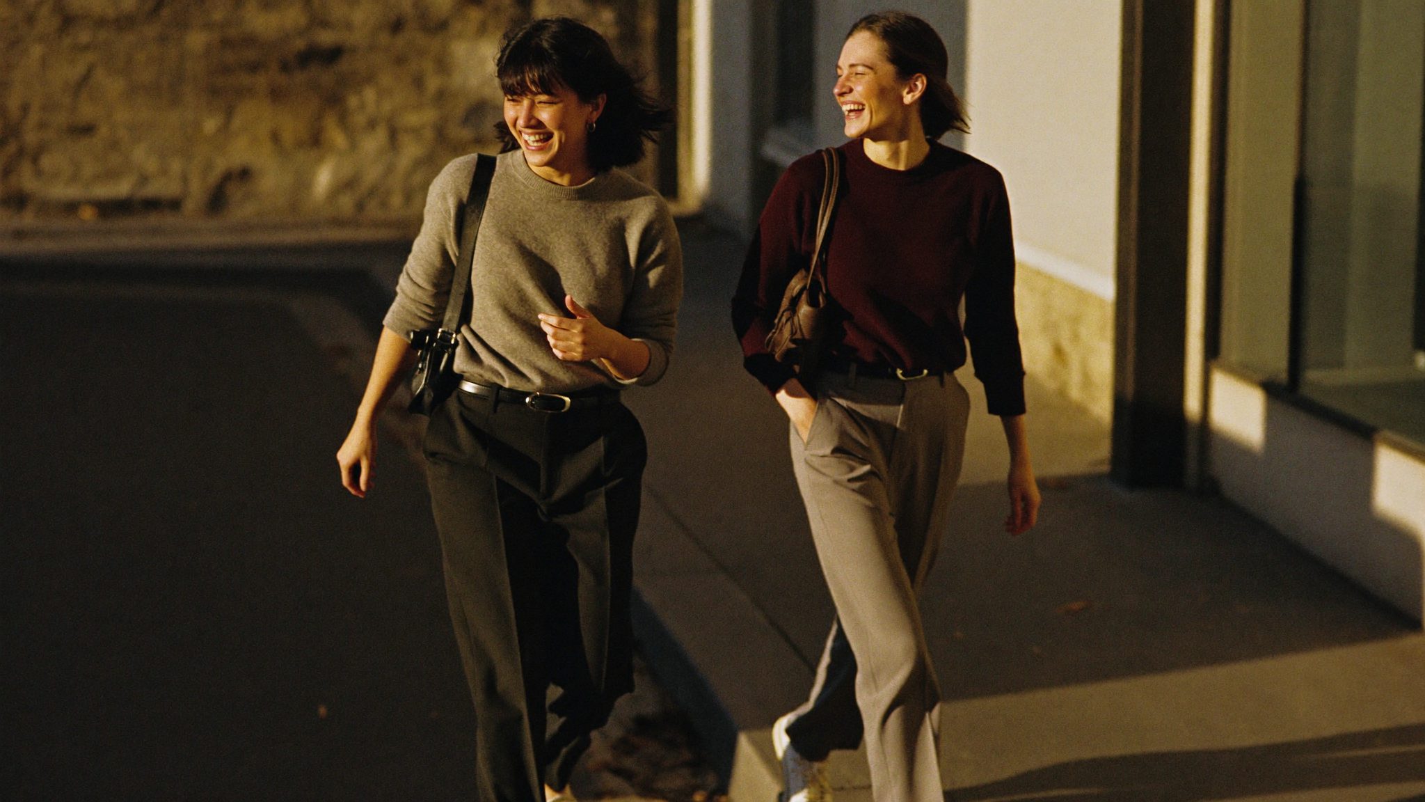 The Bloom edit: two friends walking and laughing together on a sunlit street in relaxed, premium-casual knitwear